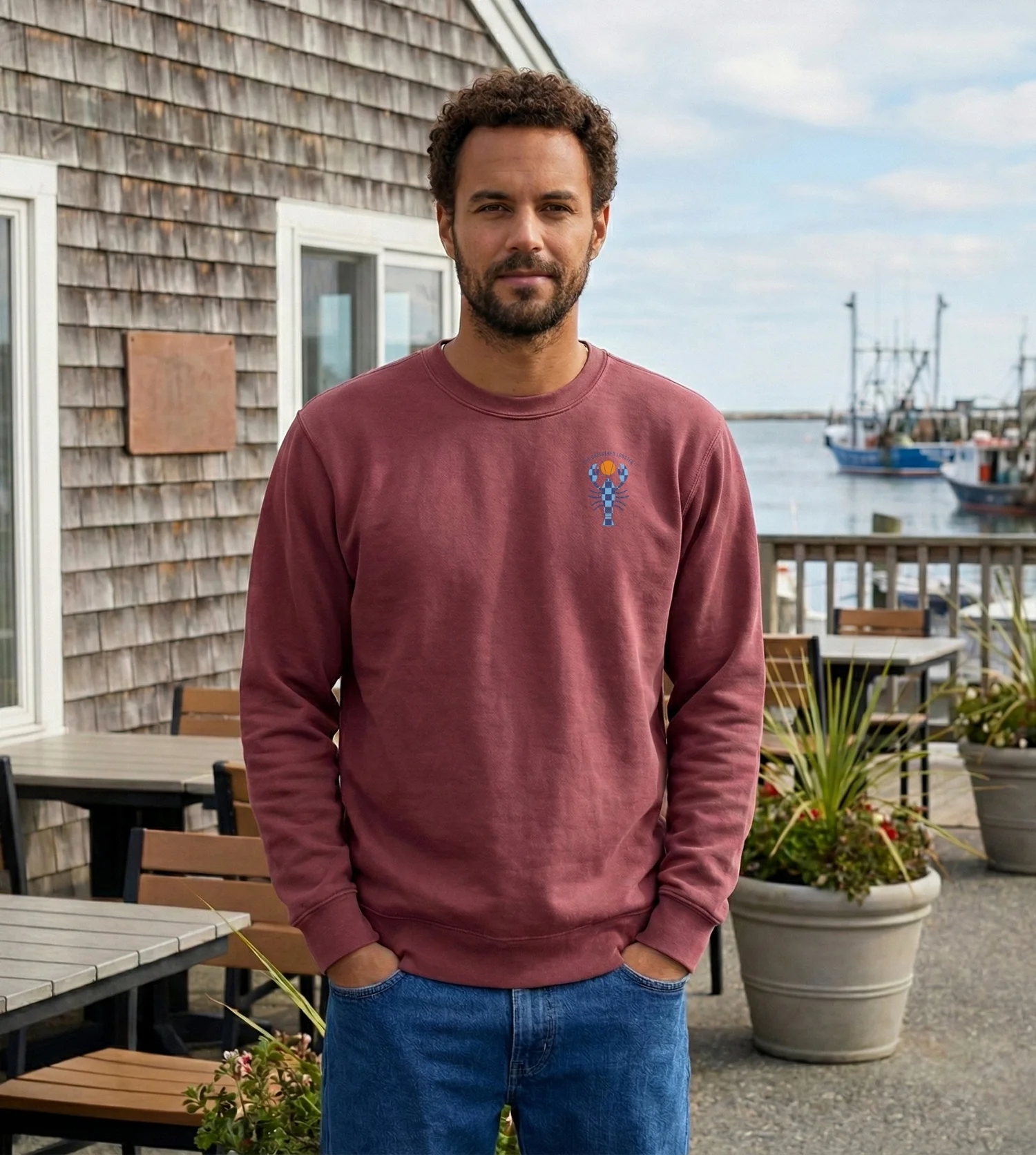 Man on a harbor deck wearing the crimson Shoreline Crew with the small Checkered Lobster at the chest