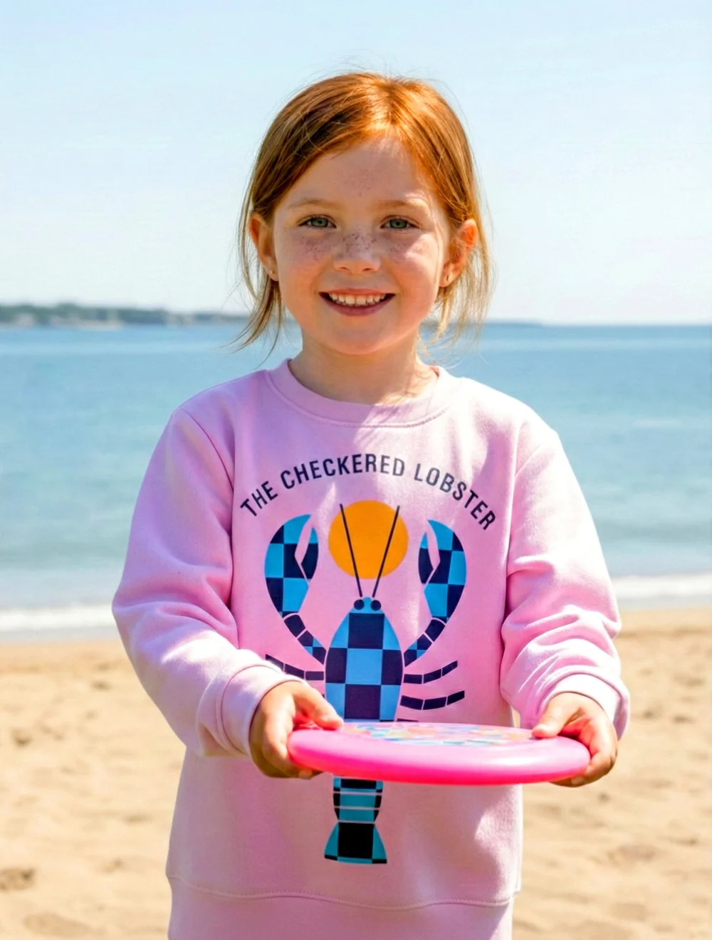 Girl on the beach wearing the Shell Pink Kids' Lobster Crewneck