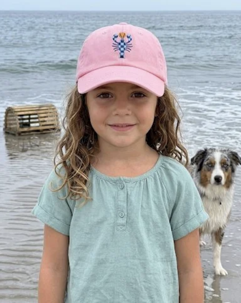 Girl at the beach with a dog wearing the Shell Pink Kids' Classic Lobster Cap